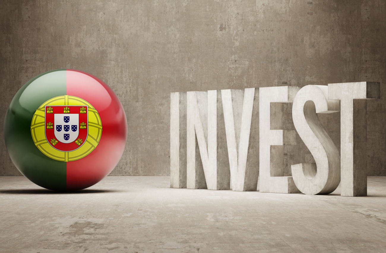 An image featuring a 3D sphere with the Portuguese flag and the word "INVEST" in bold, concrete-style letters, promoting Portugal as a destination for investment opportunities. The minimalist backdrop emphasizes the focus on financial growth and business potential.