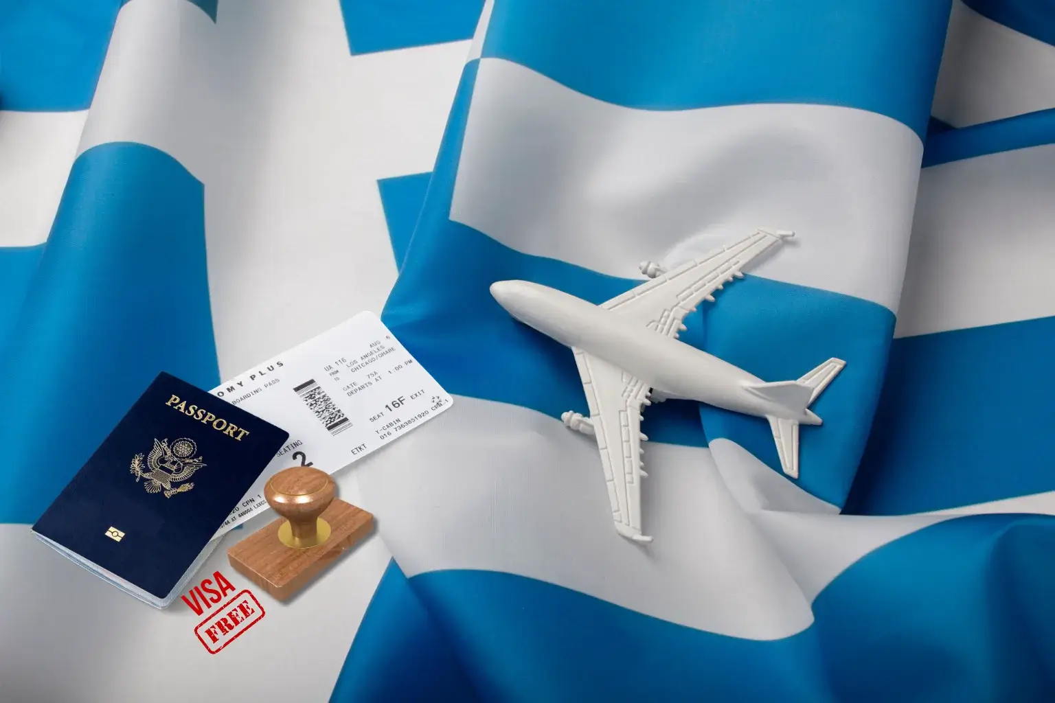 Greek flag in the background with a passport, airplane ticket, visa stamp, and a small model airplane placed on top.