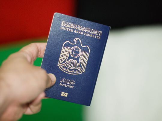 person holding UAE-Emirati-passport with uae flag in the background