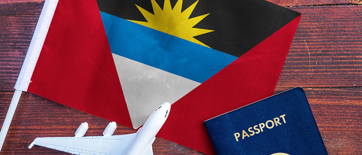 Antigua and Barbuda flag, a small model airplane, and a passport placed on a wooden surface.